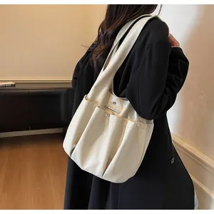 Detail view of large cream hobo bag showing pleated design and multiple pockets on strap