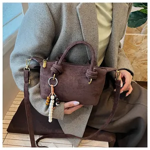 Dettaglio della borsa marrone opaco con manico a nodo e ciondolo a perline street style