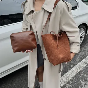 Ensemble sac seau marron givré et pochette présenté avec un mannequin dehors