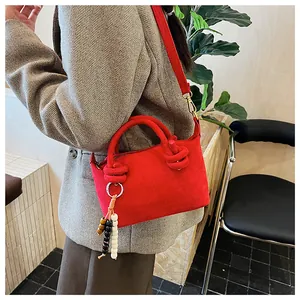 Dettaglio borsa in pelle scamosciata rossa con manico a nodo e ciondoli decorativi