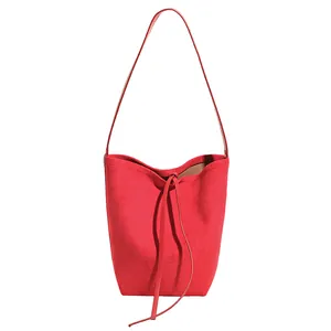 Sac seau chic en daim rouge avec longue bandoulière et détail de cordon élégant