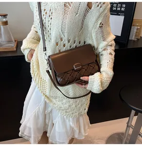 Détail d'un sac porté épaule en cuir tressé marron foncé avec une tenue élégante en tricot