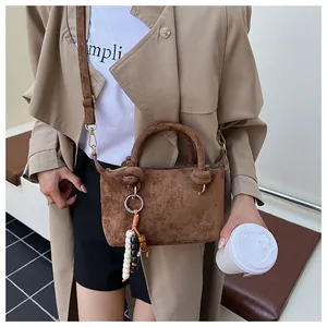Dettaglio della borsa in pelle scamosciata marrone con perline in legno e metallo oro