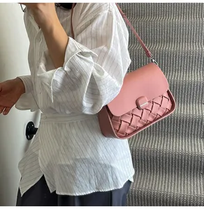 Détail du sac à bandoulière en cuir tressé rose avec boucle en métal sur le mannequin