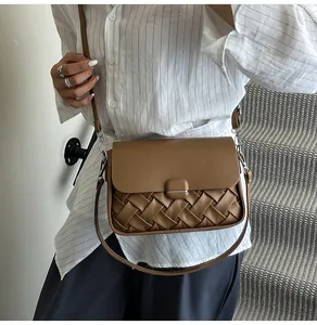 Détail du cuir tressé marron et de la boucle métallique carrée sur le sac à bandoulière