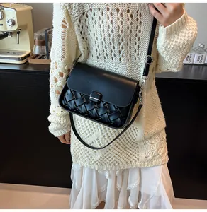 Détail du sac à bandoulière en cuir tressé noir montrant la texture et les ferrures