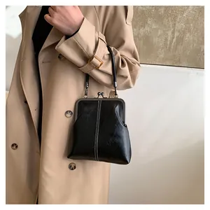 Detail of vintage black leather shell bag with ball clasp and sleek white stitching