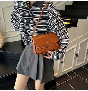 Détail du sac à bandoulière en cuir tressé marron avec boucle métallique carrée chic