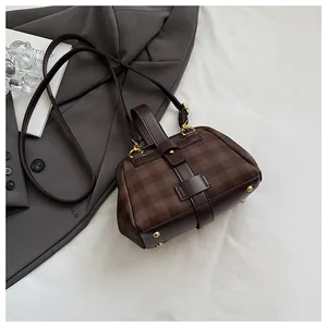 Detalle de bolso de tablero marrón con herrajes dorados y tachuelas de base protectora