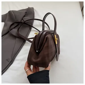 Detalle de bolso estilo doctor vintage con cuadros marrones y asas de cuero elegantes