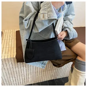 Minimalist black faux suede underarm bag shown with slim strap and stylish charm