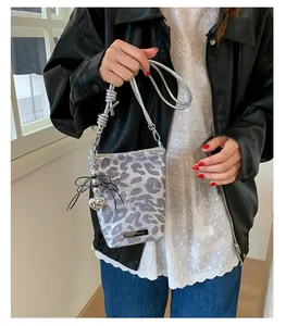 Détail du sac bandoulière léopard gris avec nœud papillon et bandoulière argentée