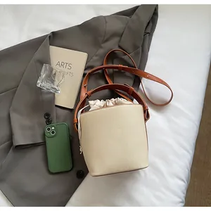 Detalle del bolso de lona con ribete de cuero marrón y cierre de cordón en un entorno minimalista