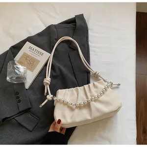 Gros plan du sac à main beige à carreaux avec chaîne de perles et bandoulière nouée