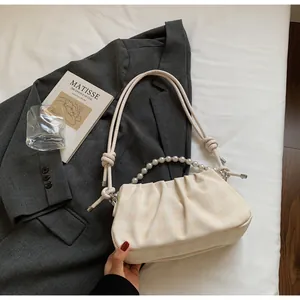 Vue détaillée du sac beige à carreaux avec poignée en perles et bandoulières nouées