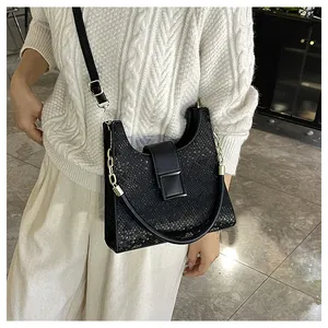 Détail du sac à main noir avec texture d'écailles, fermoir doré et chaîne métallique