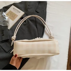 Détail du sac à main à carreaux crème avec perles et poignée en corde sur tissu gris