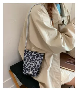Détail du sac bandoulière imprimé léopard avec chaîne argentée et plaque logo métal