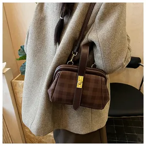 Detalle de bolso médico retro a cuadros con cierre giratorio dorado y cuero marrón