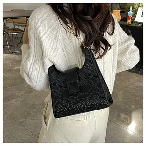 Gros plan sur la texture cuir serpent noir et la bandoulière chaîne de ce sac à main