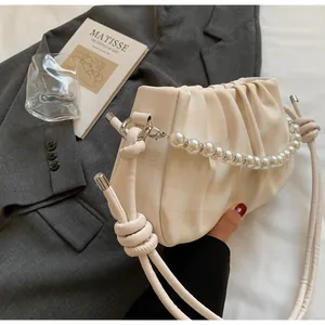 Détail d'un sac à main beige à carreaux avec anse en perles et détails plissés chics