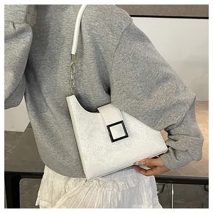 Détail du sac à main blanc asymétrique avec texture écailles et boucle carrée noire