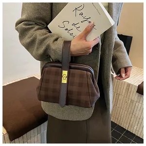Detalle de bolso retro con cuadros marrones, cierre giratorio dorado y correa de cuero