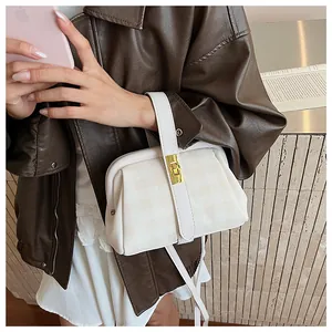 Detalle de bolso de concha beige a cuadros con hebilla dorada y asa de cuero