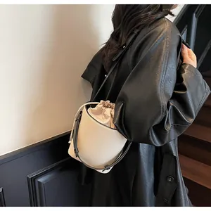 Detalle del bolso tipo cubo en crema y negro con forro de cordón y correa de cuero