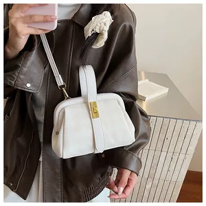 Detalle de bolso vintage crema con diseño de cuadros y cierre metálico dorado