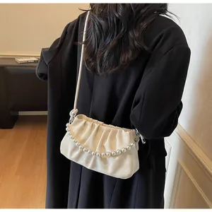 Détail d'un sac bandoulière blanc plissé avec chaîne de perles et texture à carreaux