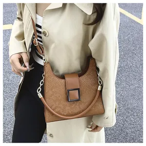 Détail du sac à main marron avec motif serpent et boucle carrée sur fond de trench-coat