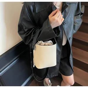Bolso tipo cubo beige chic con chaqueta de cuero en una escalera interior moderna