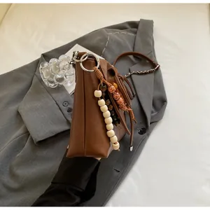 Detalle de bolso de hombro vintage marrón con borla de cuentas de madera en blazer