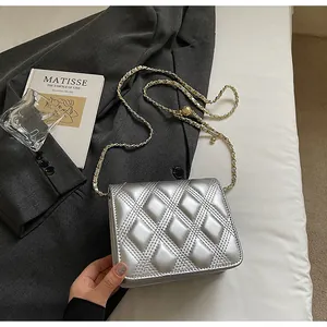 Detalle de bolso plateado acolchado con cadena sobre una chaqueta gris y atrezo de arte