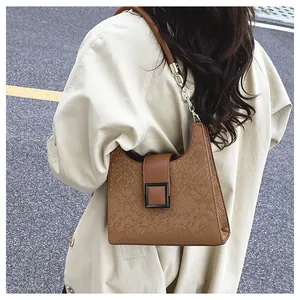 Détail du sac à main marron avec texture écaille, boucle et bandoulière chaîne