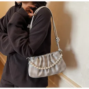 Détail du sac à main plissé argenté avec élégante chaîne de perles blanches et bandoulière nouée