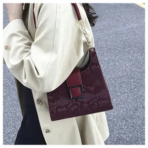 Détails du sac bordeaux avec gaufrage serpent et bandoulière en chaîne dorée