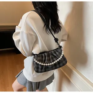 Gros plan du sac à bandoulière à carreaux gris avec chaîne en perles et sangle nouée