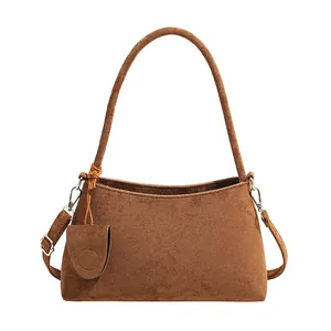 Minimalist brown suede shoulder bag with curved strap and detachable mini pouch accessory