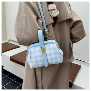 Detalle de bolso de cuadros azules con hebilla dorada sobre una gabardina caqui