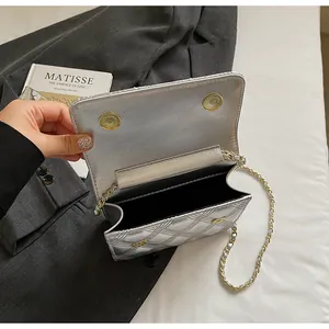 Detalle del bolso bandolera plateado acolchado con cierre magnético dorado y cadena