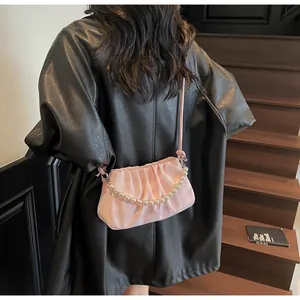 Détail du sac nuage plissé rose avec chaîne de perles sur un manteau en cuir noir