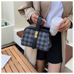Detalle del bolso tipo doctor de cuadros grises con ribete de cuero negro y cierre oro