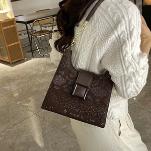Sac à épaule marron effet serpent avec chaîne dorée et boucle sur un pull blanc épais