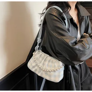 Détail du sac à main à carreaux bleu clair avec chaîne de perles sur veste noire
