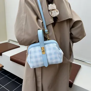 Bolso de mano de cuadros azules con correa de cuero y cierre dorado en abrigo beige