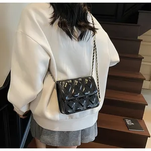 Detalle de bolso negro acolchado con cadena llevado cruzado con ropa casual