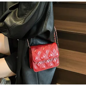 Detalle de bolso acolchado rojo con cadena sobre chaqueta de cuero negro en modelo