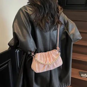 Sac nuage plissé rose avec bandoulière perle et chaîne en bandoulière porté par un mannequin